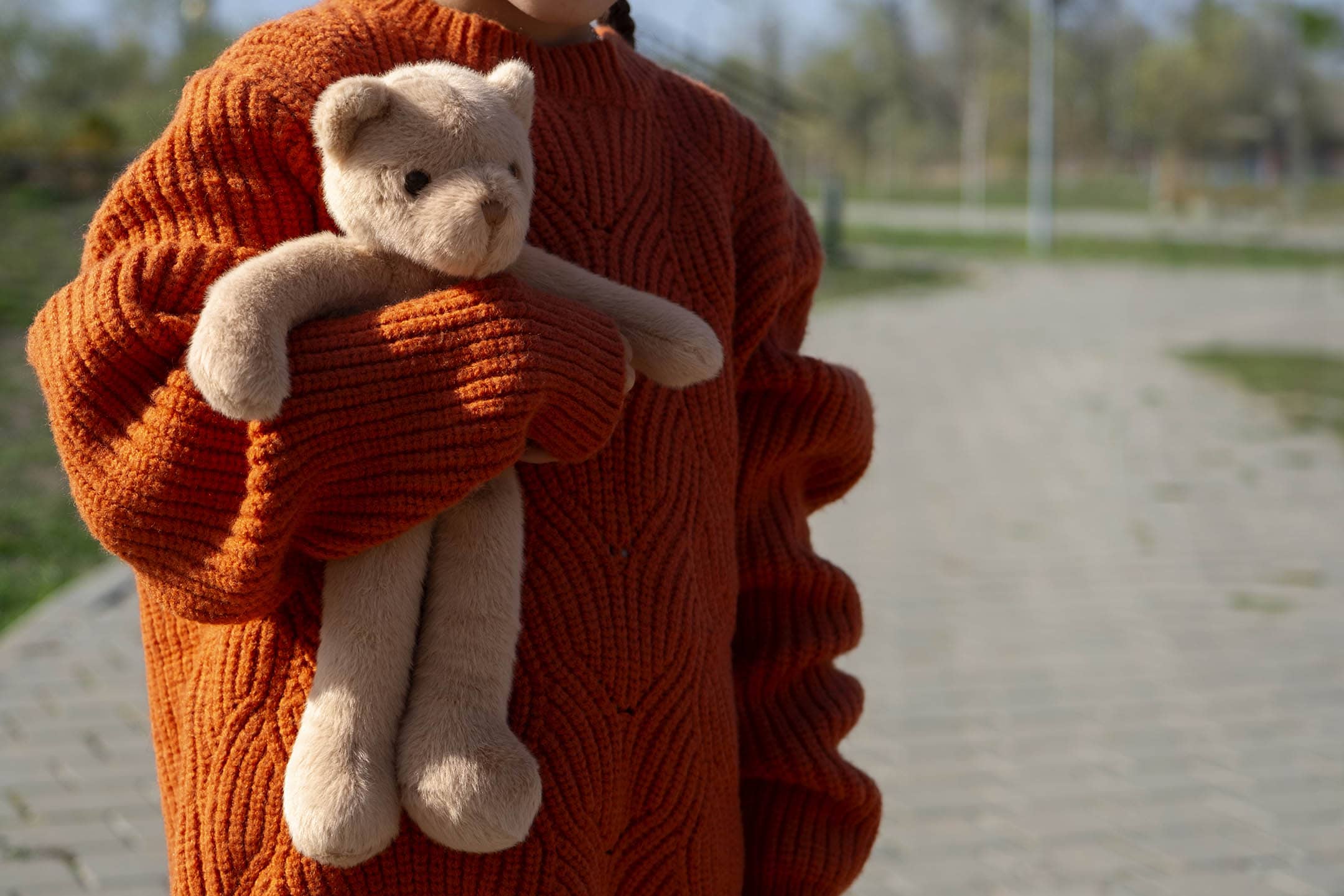 close up view kid holding teddy bear outdoors NLS